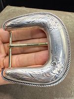 Front view of sterling silver belt buckle showing floral engraving and rope edge