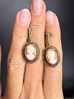 Pair of antique sterling silver cameo earrings showing carved profiles and ornate bezels