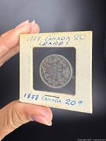 Coin in 2" cardboard coin flip marked "1858 Canada 20¢" front view showing reverse wreath and crown design