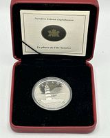 Coin in capsule inside red presentation case with COA