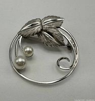 Front view of circular sterling brooch with leaves and pearls