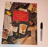 Front cover of 1990 Guinness Book of Records beside marker for scale