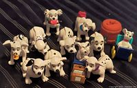 Group of twelve Dalmatian Happy Meal figurines with barrel, cart and stereo cube on striped surface