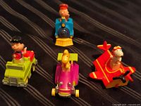 All four Peanuts Happy Meal vehicles grouped on striped surface