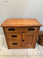 front view of wooden cabinet showing drawers, door, and hardware
