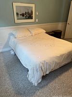 Bed made up; frame legs and wheels visible beneath mattress