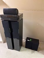 Overall view of CD player atop two tower speakers with additional bookshelf speakers nearby
