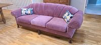 Front view of mauve channel-back sofa with pillows
