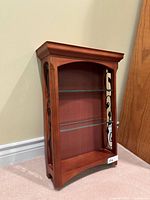 Front angled view showing wood frame, two glass shelves, scroll side panel