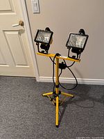 Full view of yellow tripod work light with two lamps, power cord visible
