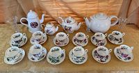 Entire lot overview showing 12 cup & saucer sets, four teapots, two crystal vases