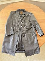 Front view of black leather coat showing buttons and pockets