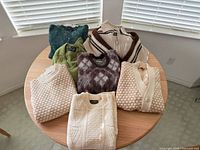 All seven sweaters folded on table showing colors and styles