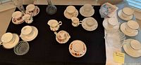 Overview of teacup sets, glass vases, small bowl and folded linens on table