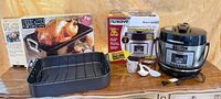 All items: boxed turkey roaster, boxed NuWave cooker, open roasting pan with rack, cooker accessories