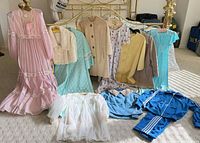 Full group shot of 14 vintage garments laid out and hanging