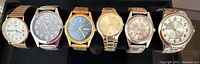 All six wristwatches lined up showing fronts and bands
