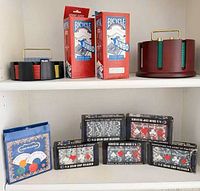 Shelf view showing playing card boxes, plastic chip rack, wooden carousel, boxed chip sets, pouch