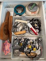 Drawer with wooden reamer, nesting cutters, plastic tub of cutters, pastry wheels, misc cutters