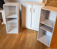 Full view of three white storage units on wooden floor