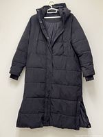 Front view of long black puffer coat hanging