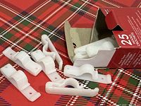 Six white plastic hooks displayed beside open red box labeled 25 hooks