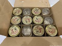 Open box showing 12 glass jars with lids in dividers