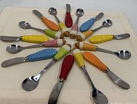 Sixteen ice-cream cone handled utensils arranged in a circle