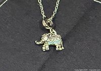 Elephant pendant on chain displayed on dark background