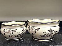 Two nested cream ceramic bowls with brown floral design