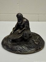 Front view of cast metal prospector figurine on circular base