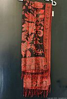 Full view of black and red floral woven scarf with fringe