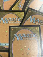 Stacked backs of Magic: The Gathering cards showing standard brown back with blue, green, red, black, and white mana dots