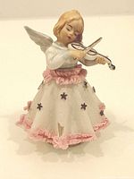Front view of porcelain angel figurine with violin and fabric skirt