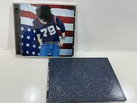 Front view of both album packages, showing jewel case cover and embossed slipcase