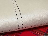 Close-up of cream faux suede surface and black dashed stitching