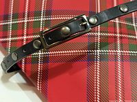 belt laid on plaid background showing studs and buckle