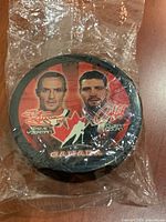 Front view showing player images and signatures on puck in plastic