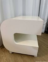 Side view showing curved C-shaped profile and lower shelf