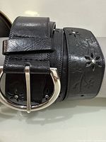 Black belt close-up showing floral cutouts and buckle