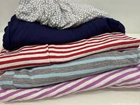 Stack of five folded tops showing patterns and colors