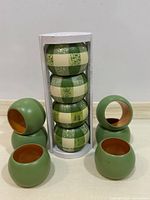 All ten wooden napkin rings—six solid green, four green/cream plaid; four plaid pieces remain stacked in original clear-tube packaging