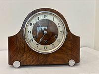 Front view of wooden mantel clock showing dial and bezel