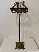 Front view of brass music stand showing full height, lyre holder, ornate base