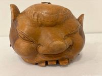 Front view of carved wood bell showing face and mouth opening