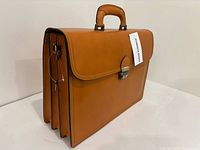 Front and side view of tan leather briefcase with handle, tag, key
