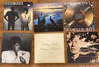 Six LP album covers laid out on wooden surface