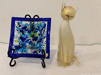 Murano glass dish on black metal stand beside Murano cat figurine