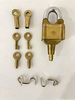 Overall view of brass puzzle lock, six brass keys and two-piece metal puzzle