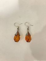 Front view of amber drop earrings with silver-tone caps and hooks